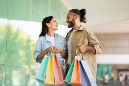 Photo for Positive millennial european lady and man shopaholics with many packages, enjoy shopping together, discount in mall. Huge sale and relationships, purchases and buyer emotions - Royalty Free Image