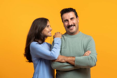 Photo for Smiling senior caucasian lady in casual looking at confident man, isolated on orange studio background. Lifestyle family, relationships and love, ad and offer, date together - Royalty Free Image