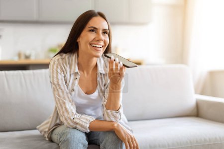 Photo for Smiling Beautiful Young Woman Recording Voice Message On Smartphone While Resting At Home, Happy Millennial Female Using Virtual Assistant On Mobile Phone, Enjoying Modern Technologies, Copy Space - Royalty Free Image