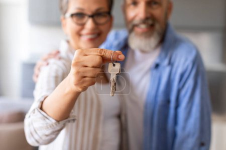 Photo for Real Estate Concept. Happy Senior Couple Holding Home Keys, Showing To Camera, Smiling Elderly Spouses Celebrating Buying Property, Moving To Their New House, Selective Focus, Cropped - Royalty Free Image