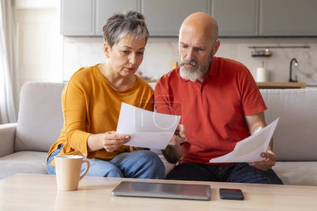 Photo for Stressed Senior Couple Checking Financial Papers And Planning Budget At Home, Upset Elderly Husband And Wife Looking At Loan Documents, Suffering Crisis While Calculating Family Spends, Closeup - Royalty Free Image