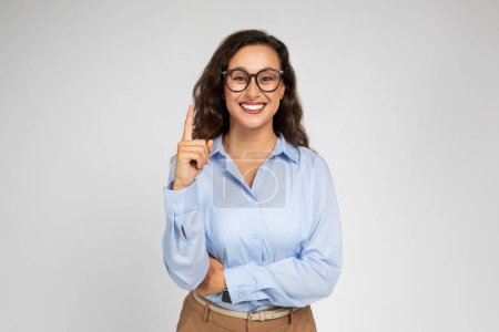 Photo for Smiling confident millennial caucasian business lady, teacher in formal wear and glasses point finger up at free space, isolated on gray background studio background. Work, got idea, solution - Royalty Free Image