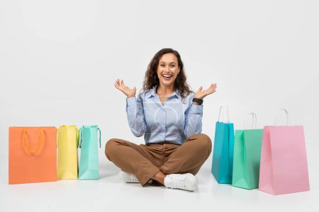 Photo for Cheerful millennial caucasian lady in formal wear, sit on floor with many purchases bags, enjoy shopping, applauses isolated on gray background studio background. Sale, buy, discount - Royalty Free Image
