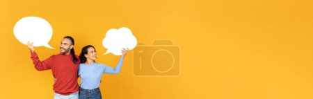 Photo for Couple relationship, male and female thoughts. Smiling young guy and woman in casual holds abstract clouds for words isolated on yellow background, panorama with copy space, mockup - Royalty Free Image