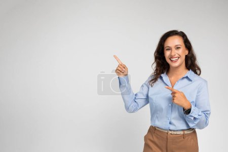 Photo for Glad young european businesswoman in formal wear pointing fingers at empty space, isolated on gray background studio background. Professional recommendation, work, attention ad and offer - Royalty Free Image