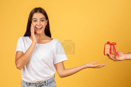 Photo for Smiling surprised young european woman take box present from man hand, isolated on yellow studio background. Gift to holidays, birthday and New Year, Xmas, Valentine day emotions - Royalty Free Image