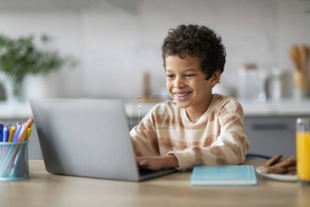 Photo for Distance Learning. Smiling Preteen Black Boy Study With Laptop At Home, Happy African American Male Child Typing On Computer Keyboard, Doing Online Homework Or Browsing Internet, Closeup - Royalty Free Image