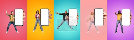 Photo for Cheerful excited young black, european and asian people show big smartphone with empty screen, jump at platform, enjoy lifestyle, isolated on multicolored background. App for fun, website - Royalty Free Image