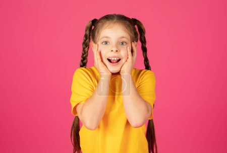 Photo for Wow. Joyful young girl with hands on her cheeks opening mouth in amazement, excited preteen female child wearing yellow t-shirt standing isolated on pink background, expressing reaction to happy news - Royalty Free Image