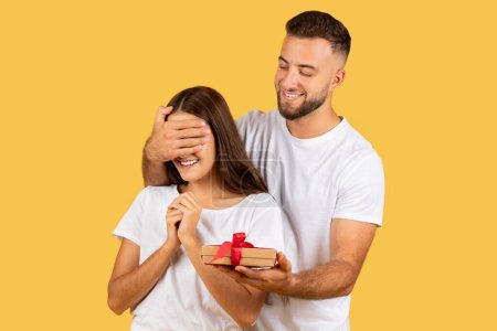 Photo for Cheerful young european man closed eyes to woman, gives box present isolated on yellow studio background. Couple enjoy holidays, birthday and New Year, Xmas gifts, Valentine day surprise - Royalty Free Image