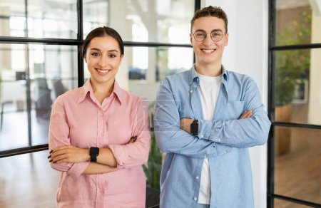 Photo for Happy confident young arab woman and european guy manager in casual with crossed arms on chest in coworking office. Startup project, team for work, business together, lifestyle - Royalty Free Image