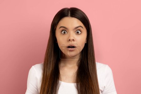 Omg. Closeup Portrait Of Shocked Teen Girl Looking At Camera With Surprise, Amazed Female Teenager Opening Mouth While Standing Over Pink Studio Background, Emotionally Reacting To News, Copy Space