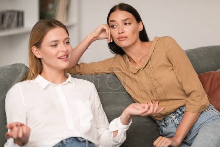 Photo for Jealous Woman Listening With Envy To Her Friend Bragging About Great Life Sitting On Sofa In Modern Living Room At Home. Envious Lousy Friends, Fake Friendship Concept. Selective Focus - Royalty Free Image