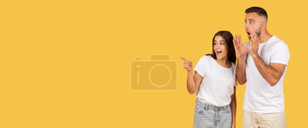 Photo for Smiling shocked millennial european woman in white t-shirts point finger at copy space to guy with open mouth, isolated on yellow studio background. Emotions surprise good news, sale, panorama - Royalty Free Image