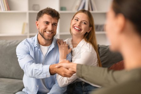 Photo for Joyful millennial spouses share a handshake with their therapist at psychotherapists office, symbolizing their progress and reconciliation after productive therapy sessions - Royalty Free Image