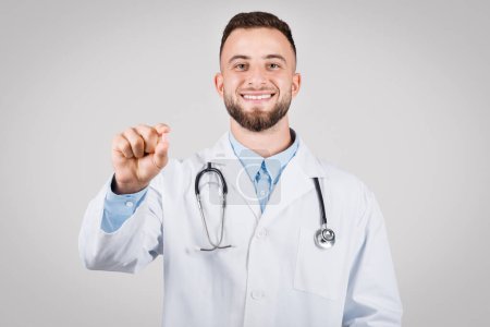 Téléchargez les photos : Médecin souriant dans un blouse de laboratoire faire un geste avec sa main qui pourrait représenter tenant la pilule ou la prescription, symbolisant le traitement médical - en image libre de droit