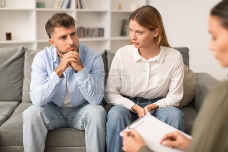 Photo for Young couple having therapy session to navigate marital issues, sitting on the sofa in psychotherapists office, spouses solving relationship conflicts with professional. Selective focus - Royalty Free Image