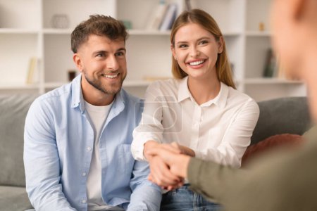 Photo for Couples therapy. Grateful husband and wife shaking hands with their therapist at psychologists office, marking successful resolution to their marital issues during a counseling session - Royalty Free Image