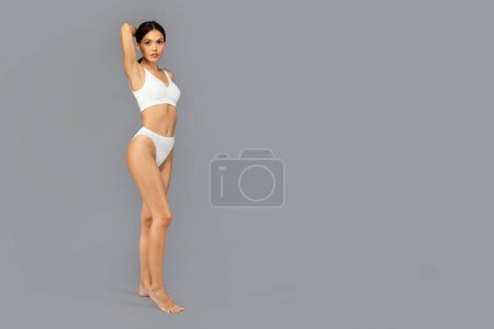 Photo for Positive caucasian slim young lady in white underwear enjoy perfect body, weight loss, fit, isolated on gray studio background, full length. Beauty care and sport, wellness - Royalty Free Image