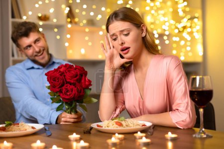 Foto de Mujer joven asombrada reacciona a ramo sorpresa de rosas del hombre sonriente, creando un momento dramático durante una cena romántica a la luz de las velas - Imagen libre de derechos