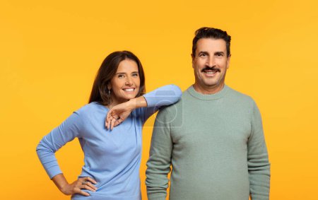 Photo for Cheerful confident european old woman rests elbow on man shoulder, smiling and approachable demeanor, isolated on orange background, studio. Support, team work, family relationship - Royalty Free Image