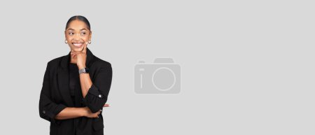 Foto de Happy pensive young african american woman in formal suit think, look at free space, enjoy work, isolated on gray studio background, panorama. Business idea creation, project - Imagen libre de derechos
