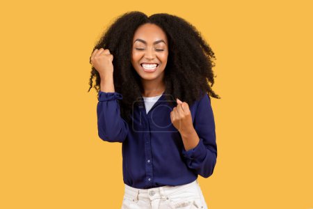 Photo for Portrait of joyful african american lady celebrating success, shaking fists and exclaiming with excitement, cheering big luck on yellow background - Royalty Free Image