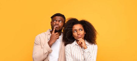 Photo for Black man and woman in thoughtful pose, touching their faces, looking sideways with quizzical expressions, against vivid yellow background, panorama - Royalty Free Image