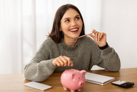 Photo for Smiling young Hispanic woman put coin into piggybank save money for vacation. Happy Latin lady manage household budget finances, make investment in piggy bank, dreaming about future - Royalty Free Image