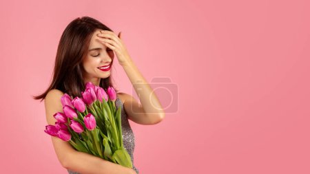 Photo for Playful young woman with a shimmering dress, laughing and holding a bouquet of pink tulips to the side, with a hand on her forehead against a pink backdrop, panorama - Royalty Free Image