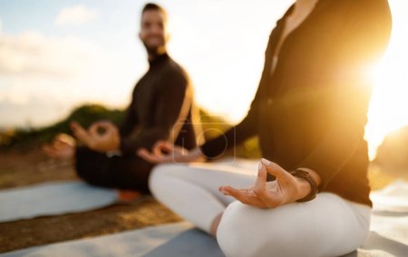 Foto de Focused close-up of a couples hands in the Gyan mudra, sitting in lotus pose, meditating during serene sunset, embodying peace and mindfulness - Imagen libre de derechos