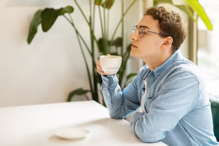 Téléchargez les photos : Young calm european man student manager in glasses drink tea, enjoy coffee cup, peace with closed eyes in modern cafe, profile. Break, routine breakfast in morning, lifestyle - en image libre de droit
