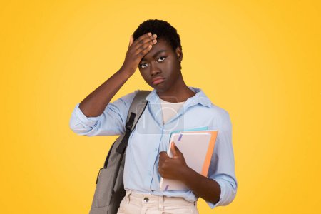 Foto de Black sad lady student with books, visibly tired and sweating, depicts exhaustion and rigors of academic life, isolated on yellow background, studio. Stress of education, problems - Imagen libre de derechos