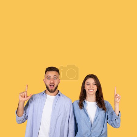 Photo for Enthusiastic man and smiling woman both point upwards, their faces alight with joy and excitement, possibly indicating new idea or opportunity against vibrant yellow backdrop - Royalty Free Image