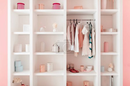 Photo for Chic open wardrobe showcases curated collection of dresses and accessories, complemented by minimalist interior with pastel accents - Royalty Free Image
