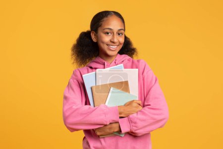 Photo for Happy African American Teen Student Girl Posing With College Work Books Smiling To Camera, Over Yellow Studio Background. Modern Education Concept, University Learner, Studentship - Royalty Free Image