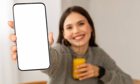 Photo for Phone with white blank screen in happy young woman hand, counting calories. Positive lady fitness showing mobile application, mockup copy space - Royalty Free Image