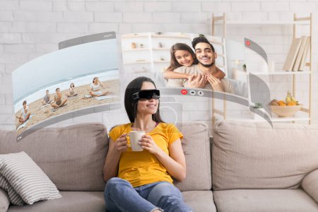 Foto de Explorando el reino virtual, la mujer joven se conecta con los miembros de la familia amados a través de chats de video inmersivos, con auriculares VR en casa - Imagen libre de derechos