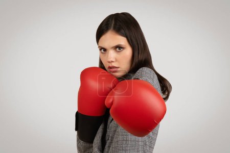 Photo for Determined young woman in business attire, poised with red boxing gloves, exuding strong defensive stance and readiness to tackle challenges head-on - Royalty Free Image