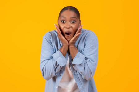Téléchargez les photos : Portrait de jeune femme noire excitée criant OMG dans l'excitation et le visage touchant sur fond de studio jaune, exprimant l'émotion de joie. Incroyable offre WOW, concept de vente énorme - en image libre de droit