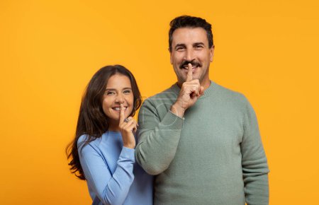Téléchargez les photos : Souriant vieux caucasien homme et femme en tenue décontractée rire ensemble sur un fond orange vibrant, incarnant la chaleur, le bonheur, et une relation positive, studio - en image libre de droit