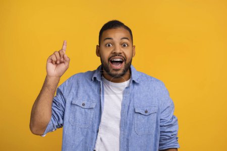 Photo for Idea Concept. Excited Young Black Man Pointing Finger Up And Looking At Camera, Happy Handsome African American Male Found Problem Solution, Having Inspiration, Posing On Yellow Studio Background - Royalty Free Image