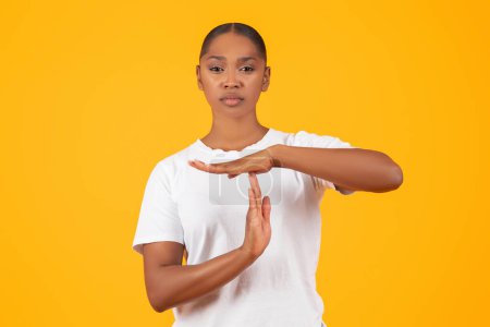 Photo for Timeout concept. Serious Young Black Woman Showing Time Out Hand Gesture While Standing Over Yellow Background In Studio, Looking At Camera With Determined Strict Expression. I Need A Break - Royalty Free Image