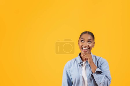 Photo for I Think. Dreamy african american young woman looking up at free space for text advertisement, thinking about great offer touching her chin, isolated over yellow studio background, copyspace - Royalty Free Image