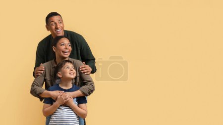 Photo for Excited father, mother and son embracing, standing one behind another, looking at copy space for advertisement, beige studio background. Great family offer, deal, panorama, banner - Royalty Free Image