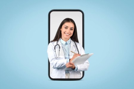 Photo for Friendly female doctor in white uniform with stethoscope and clipboard, writing prescription to patient and smiling at camera, looking coming out huge cellphone screen - Royalty Free Image