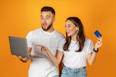 Photo for Happy young european man and woman shopaholics in casual use laptop, credit card, enjoy shopping, isolated on orange background studio. Recommendation sale, pay and buy remotely - Royalty Free Image