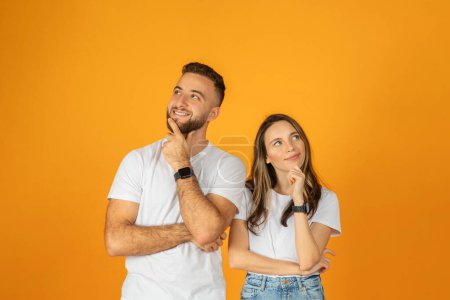 Photo for Happy pensive young european guy and woman think, look at free space, isolated on orange background studio. Positive lifestyle, love, romance and relationship, creation idea, brainstorm - Royalty Free Image