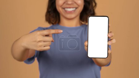 Foto de Aplicación móvil, oferta en línea. Recortado de mujer de Oriente Medio apuntando a teléfono inteligente con blanco pantalla en blanco espacio de copia maqueta para el anuncio en la mano, aislado en el fondo colorido - Imagen libre de derechos