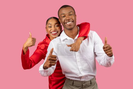 Téléchargez les photos : Couple noir joyeux avec les pouces levés, femme en chemisier rouge et homme en chemise blanche, partager confiant, moment heureux ensemble sur fond rose - en image libre de droit
